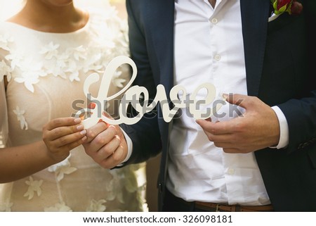 Closeup photo of bride and groom holding word Love