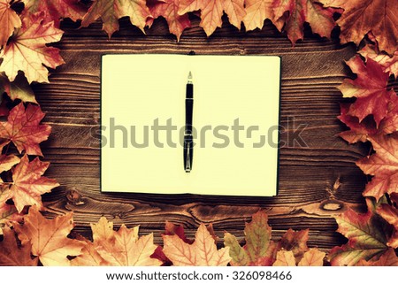 diary and pen with fallen leaves on wooden background, top view, copy space. free space for text