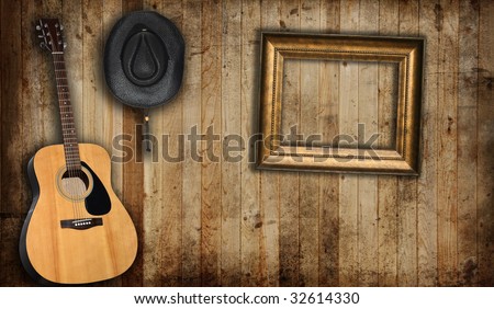 Cowboy hat, guitar and empty picture frame, against an old barn background.