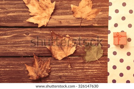 Leafs and gift on wooden table.