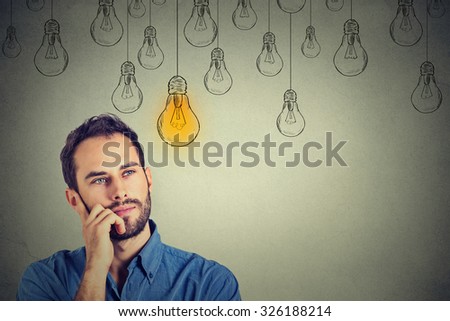 Portrait thinking handsome man looking up with idea light bulb above head isolated on gray wall background Royalty-Free Stock Photo #326188214
