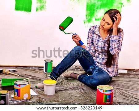 Unhappy sad tired woman paint wall at home.