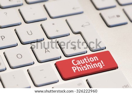 computer keyboard with the words caution phishing on red key