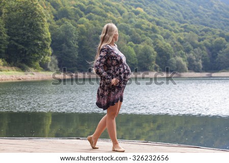 Young beautiful pregnant woman posing at the lake