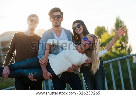 Just having fun. Group of cheerful young people having fun and looking at camera while standing outdoors  together