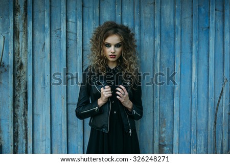 Vintage woman as witch, posing against the backdrop of an abandoned place on the eve of Halloween