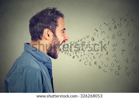 Side profile portrait of young angry man screaming with alphabet letters flying out of wide open mouth isolated on gray wall background  Royalty-Free Stock Photo #326268053