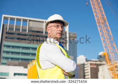 Confident construction engineer in hardhat with arms crossed on chest