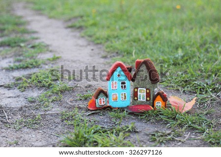 toy houses and autumn leaves on green grass