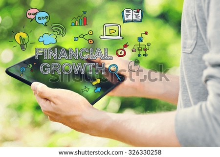 Financial Growth concept with young man holding his tablet computer outside in the park