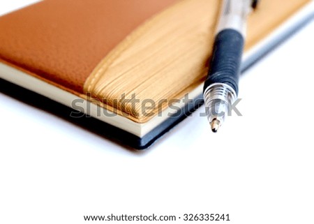 closeup and blur image of pen on brown notebook in soft focusing