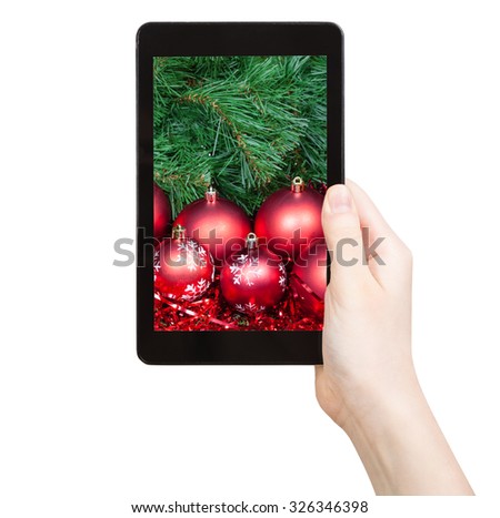 hand holds tablet pc with red Christmas baubles on screen isolated on white background