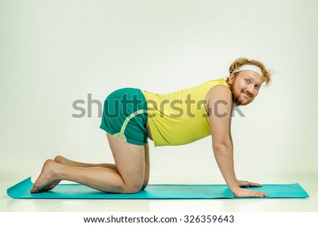 Funny picture of red haired, bearded, plump man on white background. Man wearing sportswear. Man trains on the mat.
