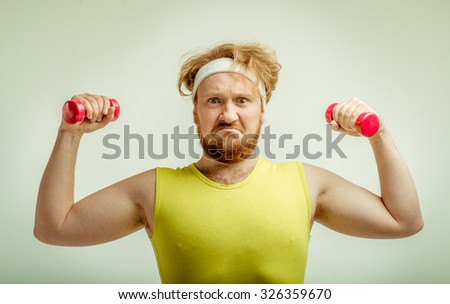 Funny picture of red haired, bearded, plump man on white background. Man wearing sportswear. Man holding the dumbbells
