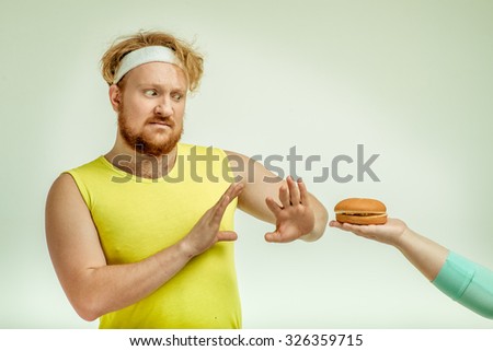 Funny picture of red haired, bearded, plump man on white background.  A human giving a sandwich for man, but man doesn't want to take it