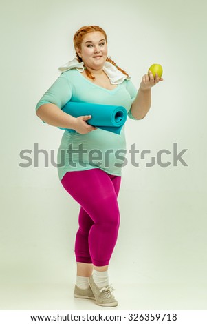 Funny picture of amusing, red haired, chubby woman on white background. Woman holding a mat.