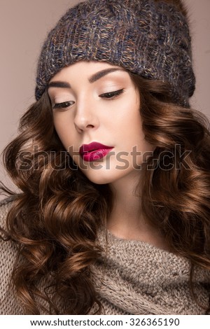 Beautiful girl with gentle makeup, curls in brown knit hat. Warm winter image. Beauty face. 