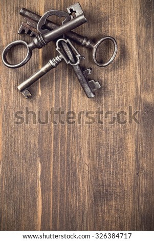 Old keys at left top corner of wooden background top view vertical toned