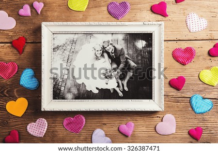 Picture frame with wedding photo. Studio shot on wooden background.