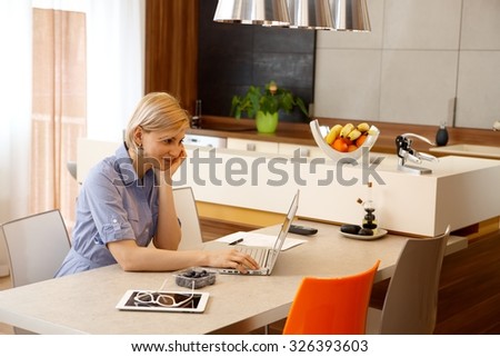 Young woman using laptop computer at home, smiling.