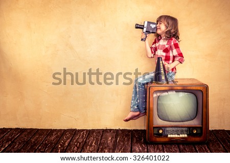 Child playing at home. Kid making a film with retro camera. Cinema concept Royalty-Free Stock Photo #326401022