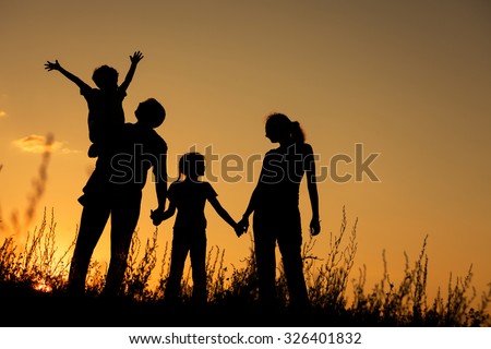 Happy family standing in the park at the sunset time.  Concept of friendly family.