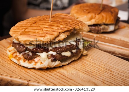 Two Hamburgers Served On Wooden Plate