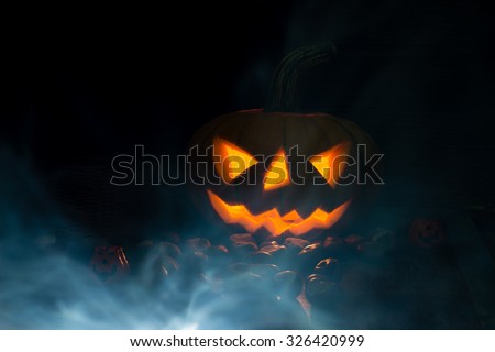 Halloween pumpkin face lantern at night with misty smoke. Halloween background. Royalty-Free Stock Photo #326420999