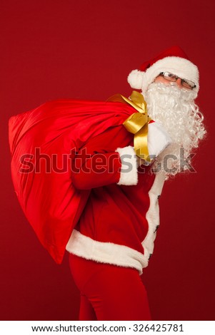 santa claus with big bag on shoulder glasses on red background