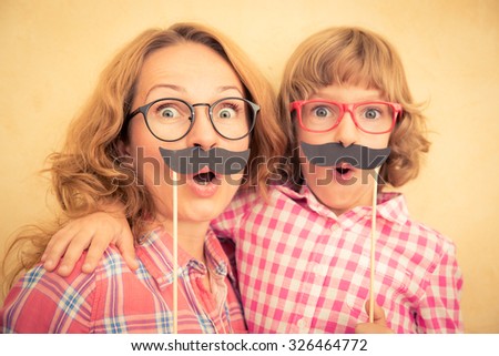 Mother and child with fake mustache. Happy family playing in home  Royalty-Free Stock Photo #326464772