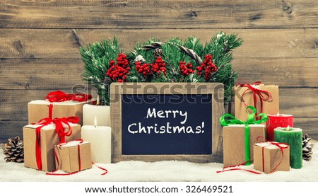 Christmas decoration burning candles and gift boxes. Blackboard with sample text Merry Christmas! Vintage style toned picture