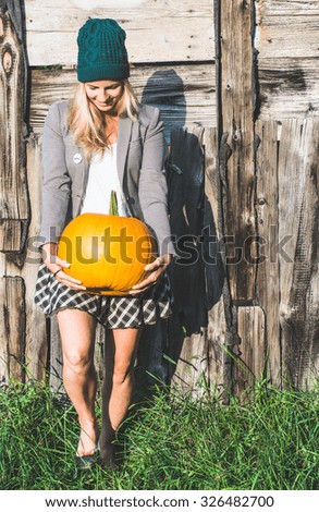 Blonde woman holding halloween pumpkin outdoor