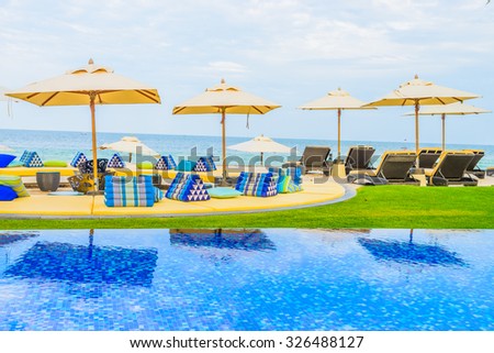 Hotel resort swimming pool with umbrella and chair on the beach