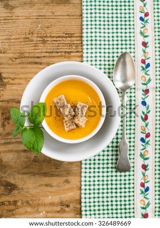 Homemade pumpkin soup with croutons on a wooden table
