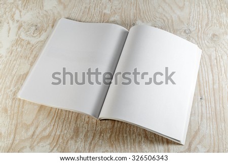 Blank opened brochure magazine on wooden background with soft shadows. Mock-up for graphic designers portfolios.