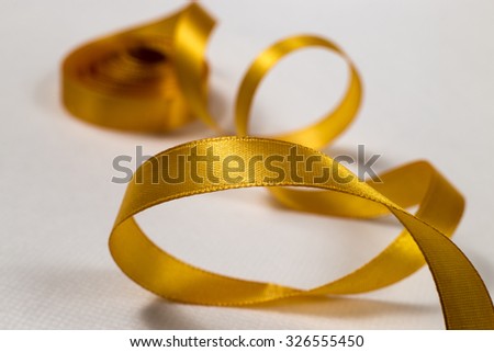 Close-up of yellow ribbon unraveling on white background