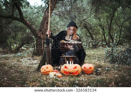 young woman in halloween witch costume in forest