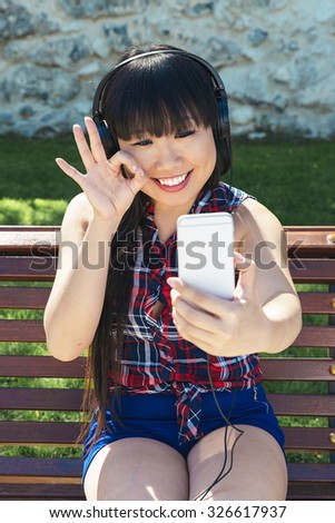 Asian woman taking self portrait selfie photo on park. She is happy
