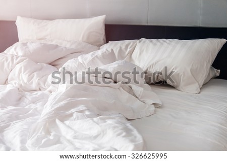 white pillow on bed and with wrinkle messy blanket in bedroom, from sleeping in a long night. Royalty-Free Stock Photo #326625995