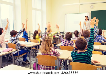 education, elementary school, learning and people concept - group of school kids with teacher sitting in classroom and raising hands Royalty-Free Stock Photo #326638589