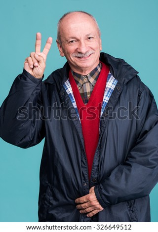 Portrait of a senior man showing ok sign on blue background