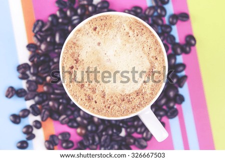 Coffee cup with coffee beans. Cross processed image with shallow depth of field