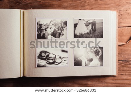 Wedding photos in album. Studio shot on wooden background.