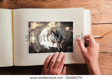 Picture of bride and groom in photo album. Studio shot on wooden background.