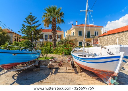 Fishing boats in dock of Pythagorion port with traditional colourful Greek houses in background, Samos island, Greece