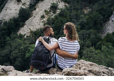 Image of people who are sitting on a big rock while looking on the landscape