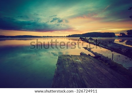 Vintage photo of beautiful sunset over calm lake in Mazury lake district. Photo with vintage mood effect.