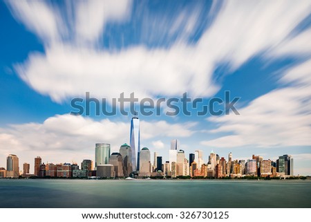 The cityscape of New York as viewed from New Jersey with running clouds on bright blue sky
