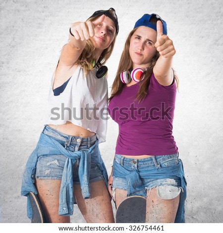 Two friends with their skateboards with thumb up 