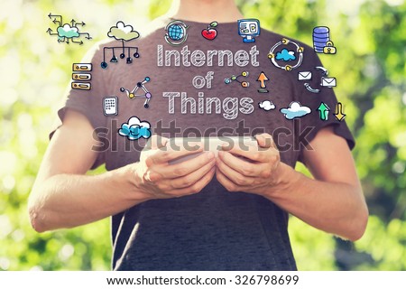 Internet of Things concept with young man holding his smartphone outside in the park toward sunset Royalty-Free Stock Photo #326798699